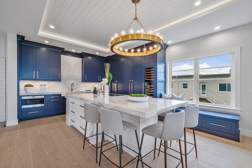 Modern kitchen with blue cabinets, white island, and gold chandelier.