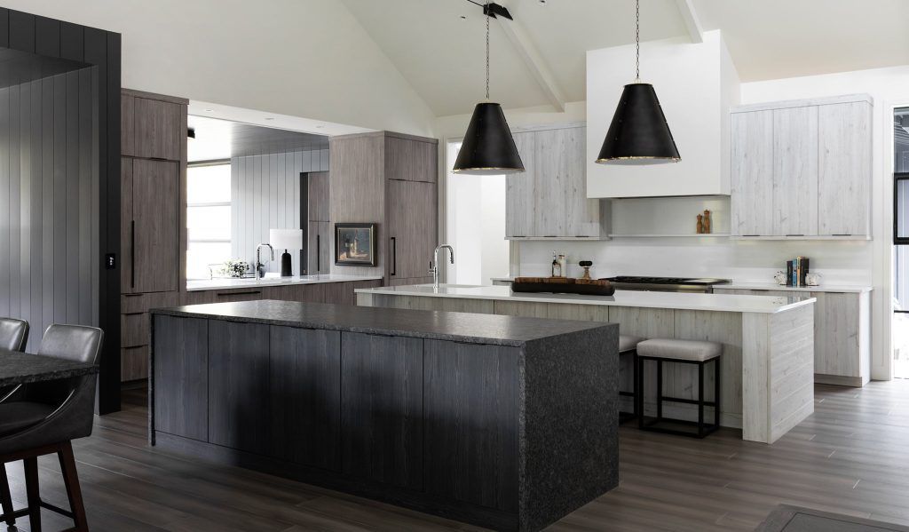 Modern kitchen with large dark island, light wood cabinets, black pendant lights.