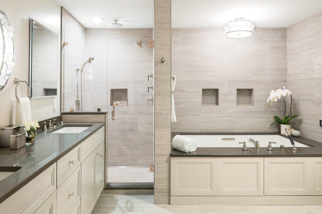 Bathroom with gray countertop and backsplash, glass shower, and tub with white orchid.