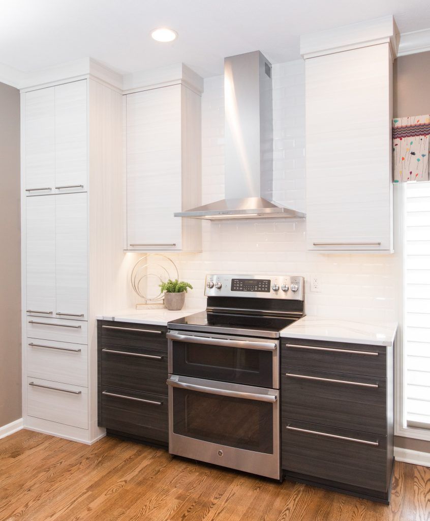 Modern kitchen with stainless steel appliances, white and dark gray cabinets, and light countertops.