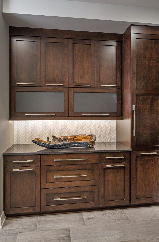 Dark wood kitchen cabinets with a countertop and decorative bowl, lit from below.