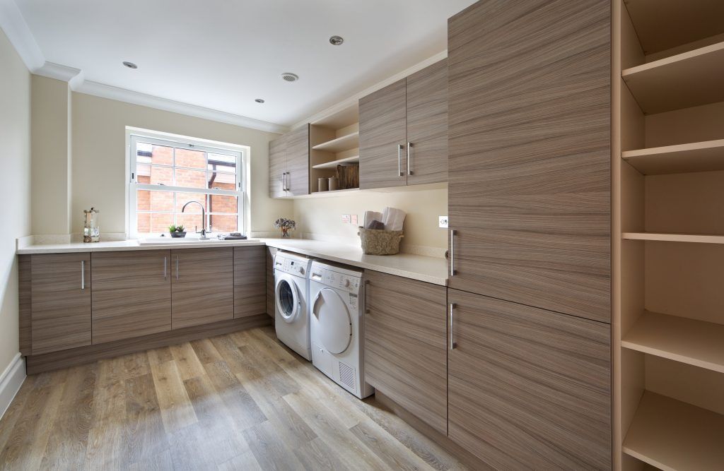Laundry room with light wood cabinets, washer/dryer, shelving, and a window.