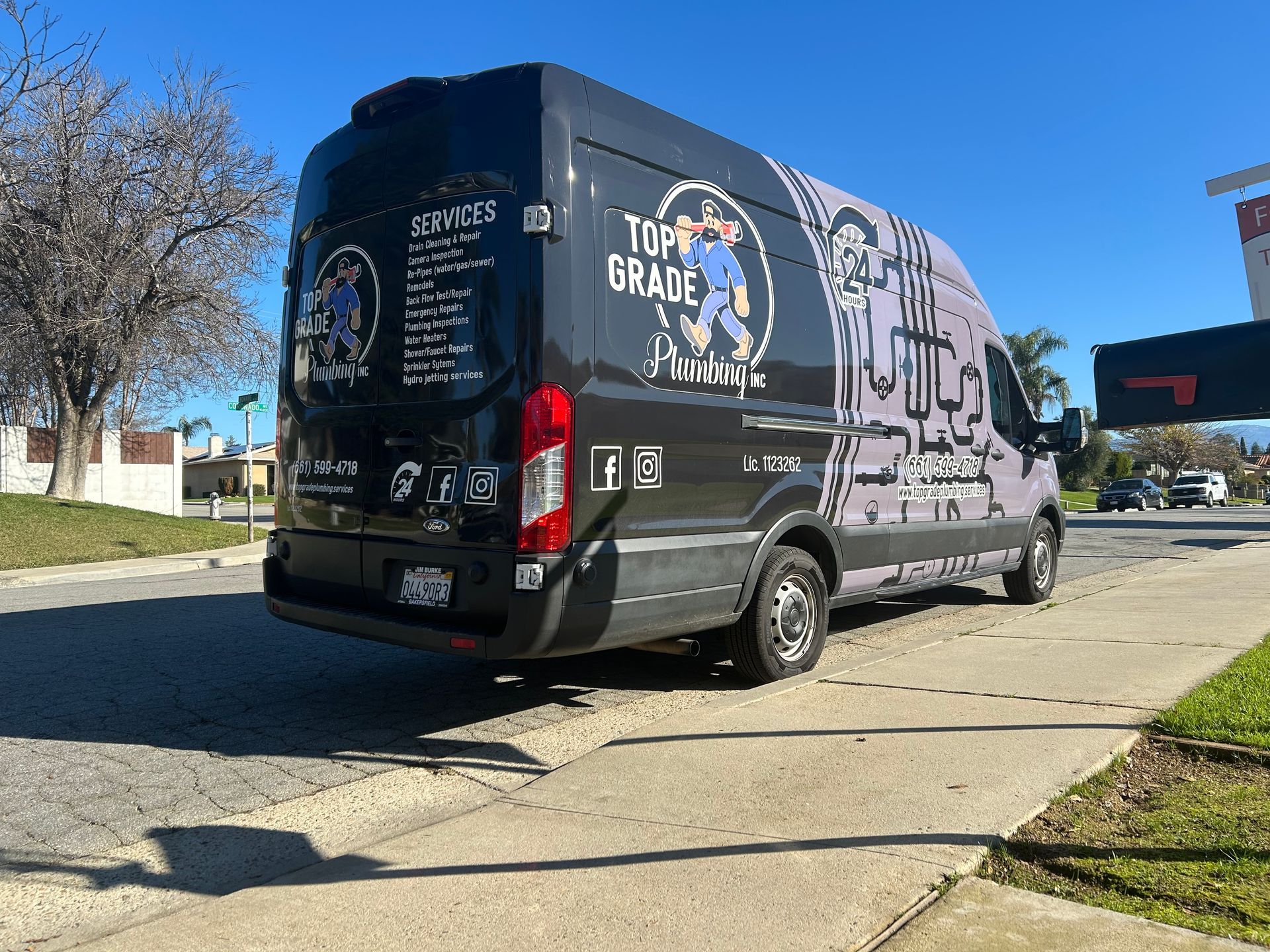 Black delivery van with colorful graphics parked on a sunny suburban street.