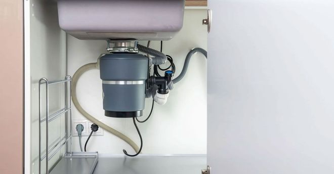Under-sink water filtration system with gray tank and tubing in a cabinet