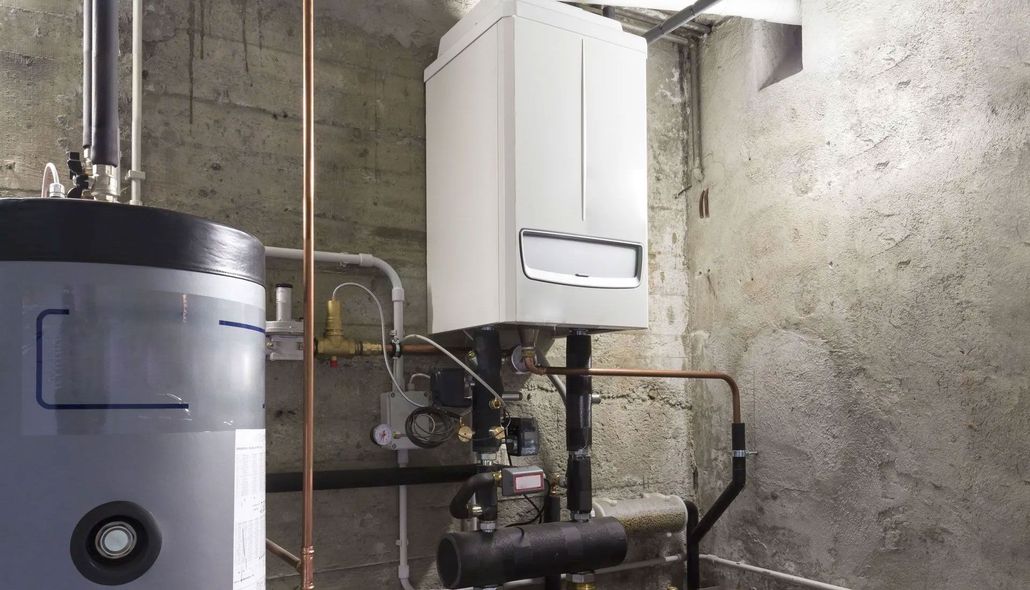 Basement utility room with water heater, boiler, exposed pipes, and concrete walls