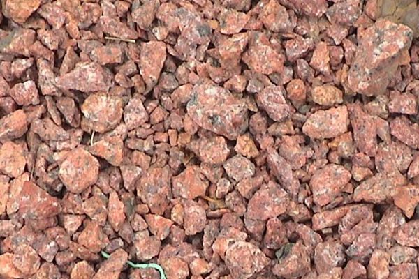 A pile of red rocks is sitting on the ground.