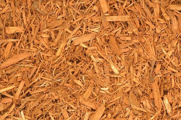 A pile of brown mulch is sitting on the ground.