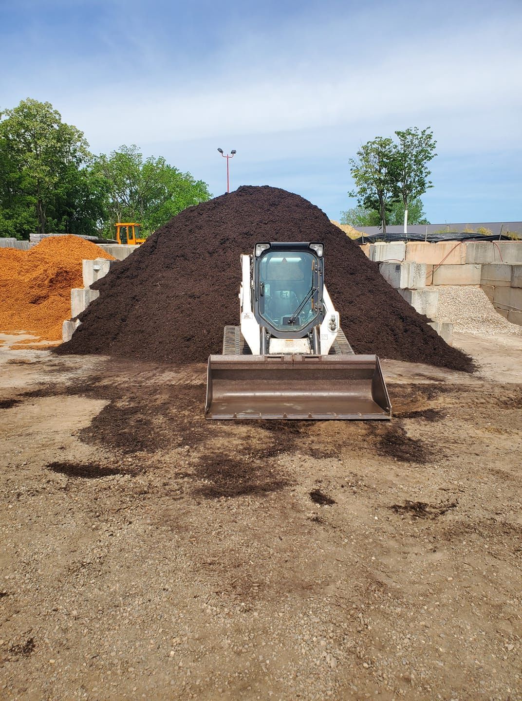 A bulldozer is sitting in front of a pile of mulch.