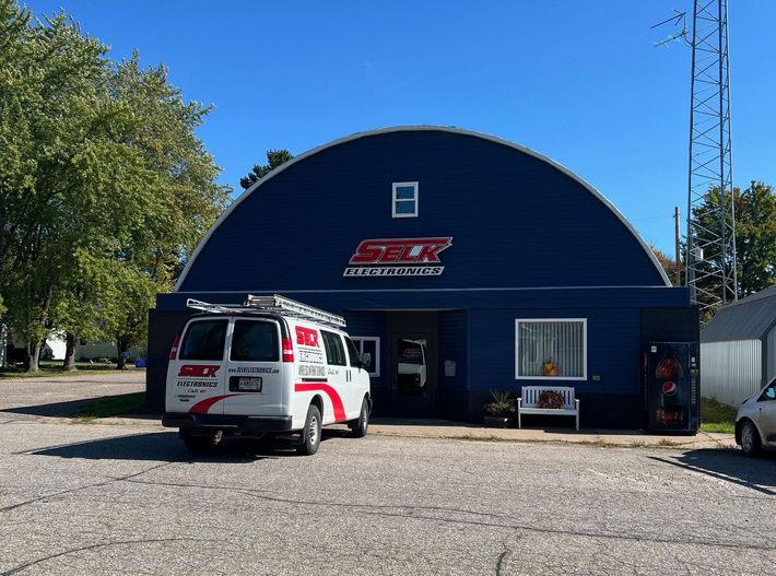 A white van is parked in front of a blue building.