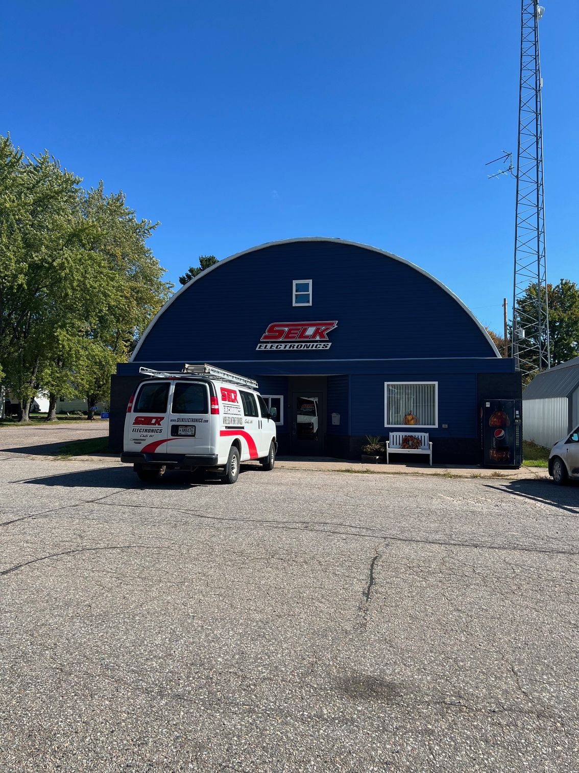 A white van is parked in front of a blue building.