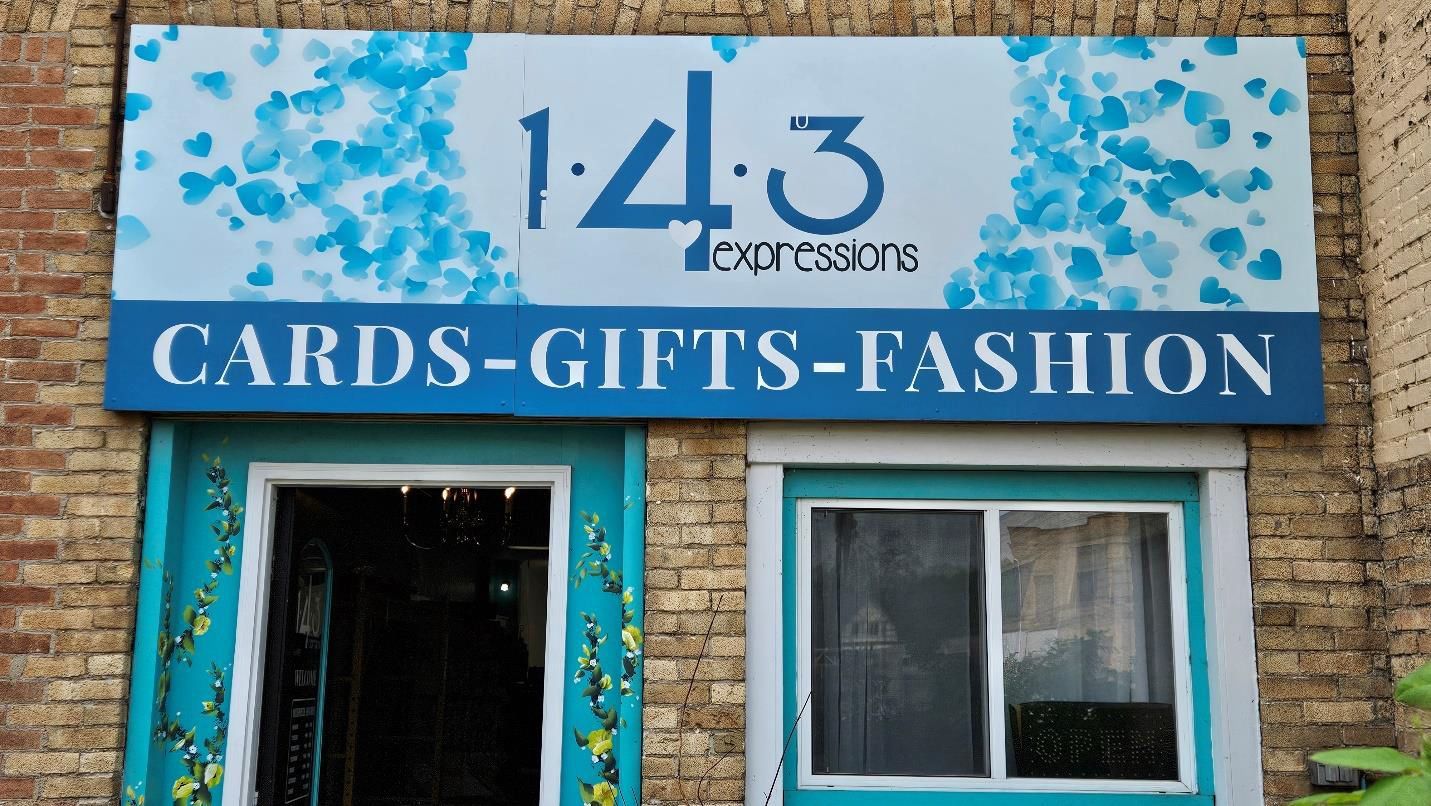 Storefront sign for 143 Expressions selling cards, gifts, and fashion, above a doorway and window on a brick building.