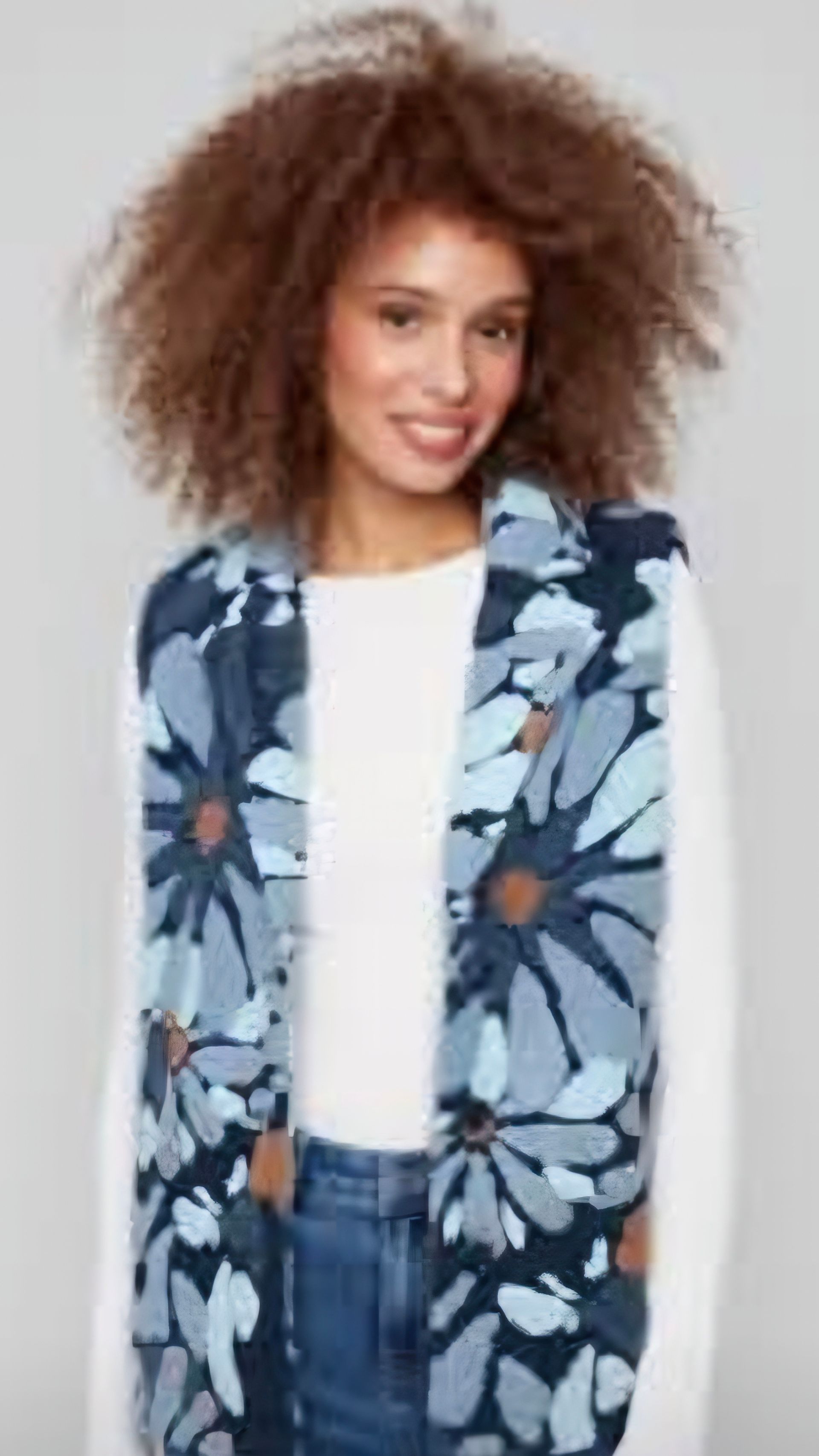 Woman wearing a blue floral scarf, smiling, with brown curly hair and a white shirt.