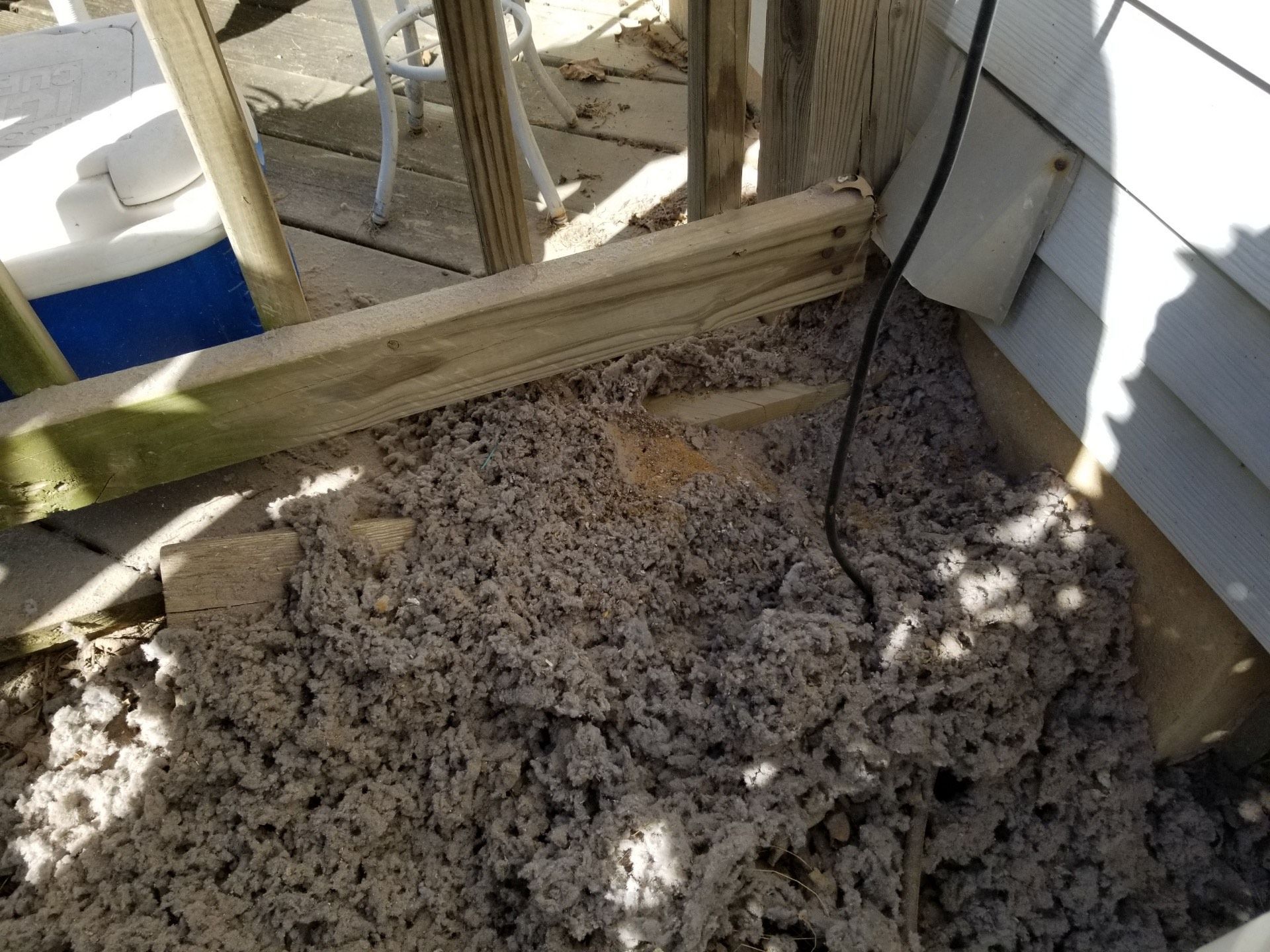 A pile of insulation is sitting on the ground next to a wooden structure.