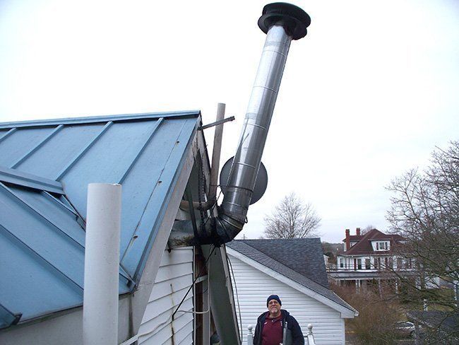 A man standing next to a chimney on the side of a house