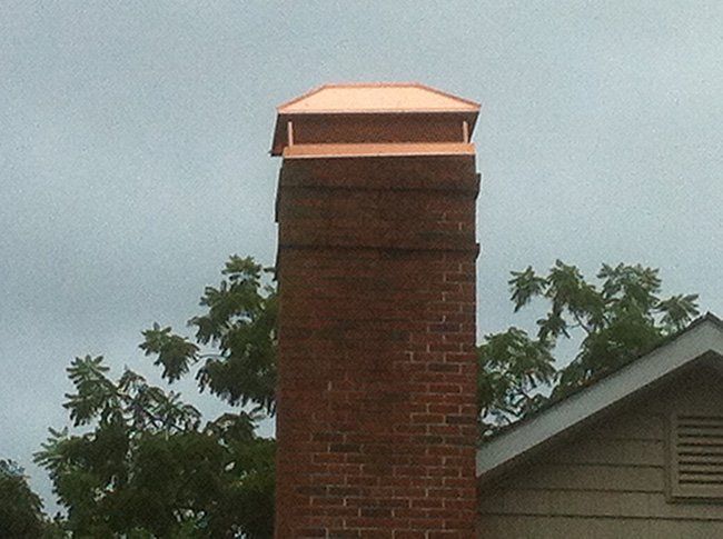 A brick chimney with a copper cap on top of it