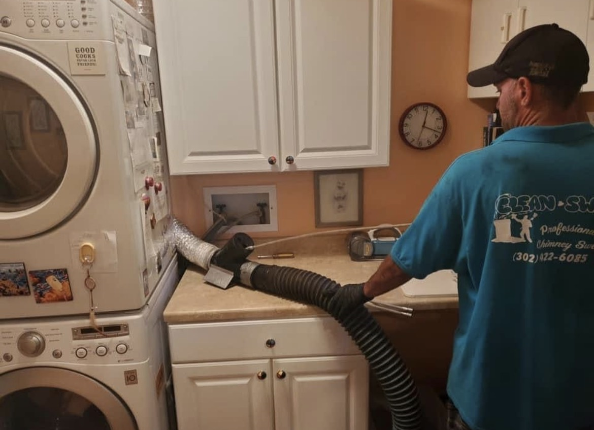 A man in a blue shirt is using a vacuum cleaner in a laundry room.