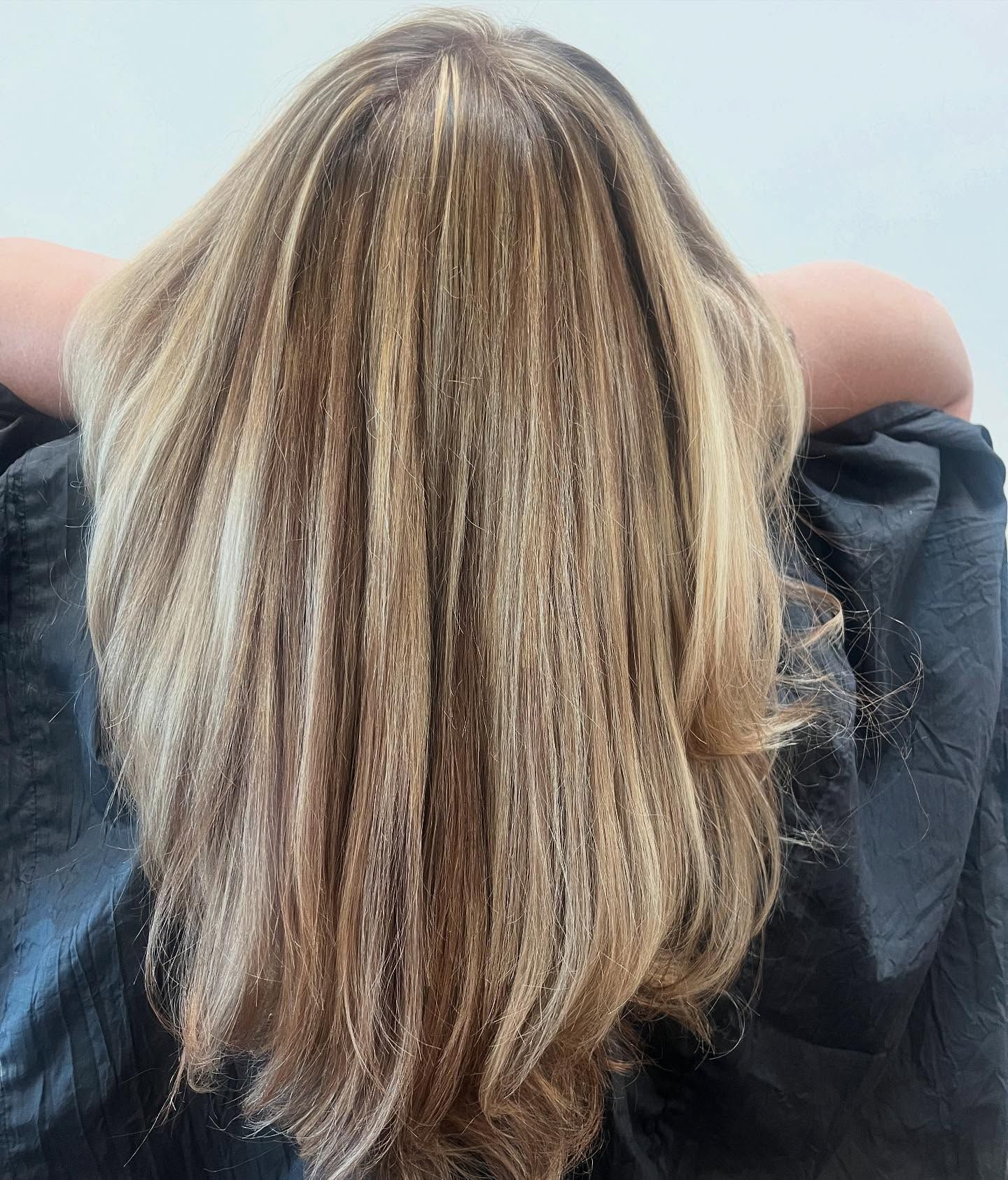 Long, highlighted blonde hair draped over shoulders, in a salon setting.