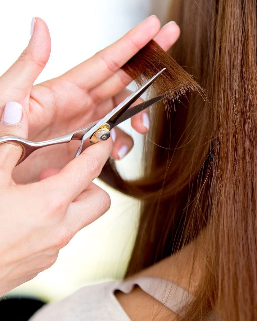 Hairdresser cutting brown hair with scissors. Close-up.