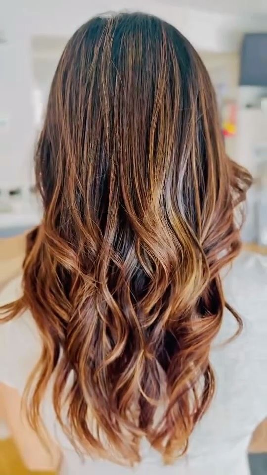 Brown hair with a balayage effect, styled in loose waves.