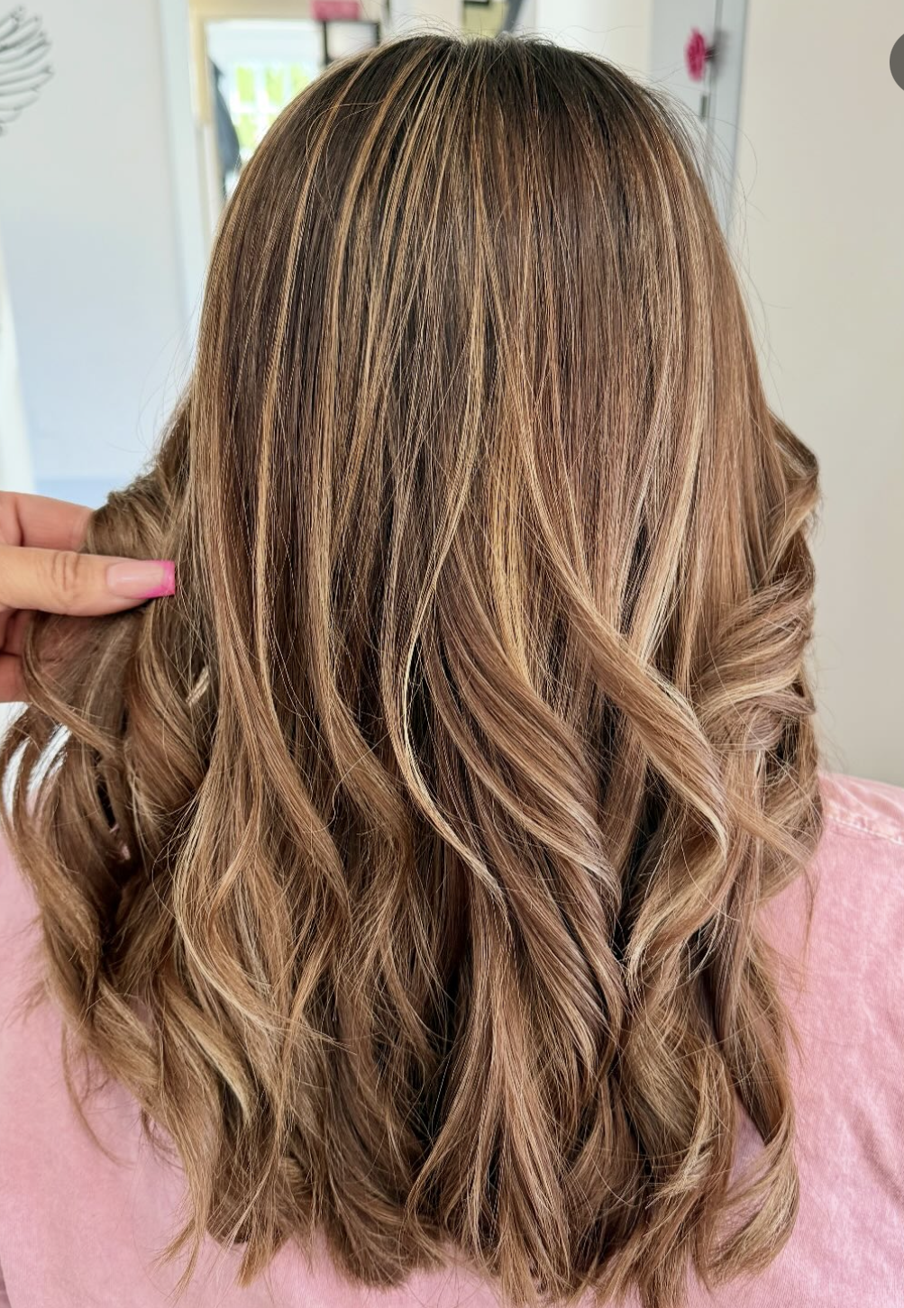 Brown wavy hair with crimped top section, held by a hand