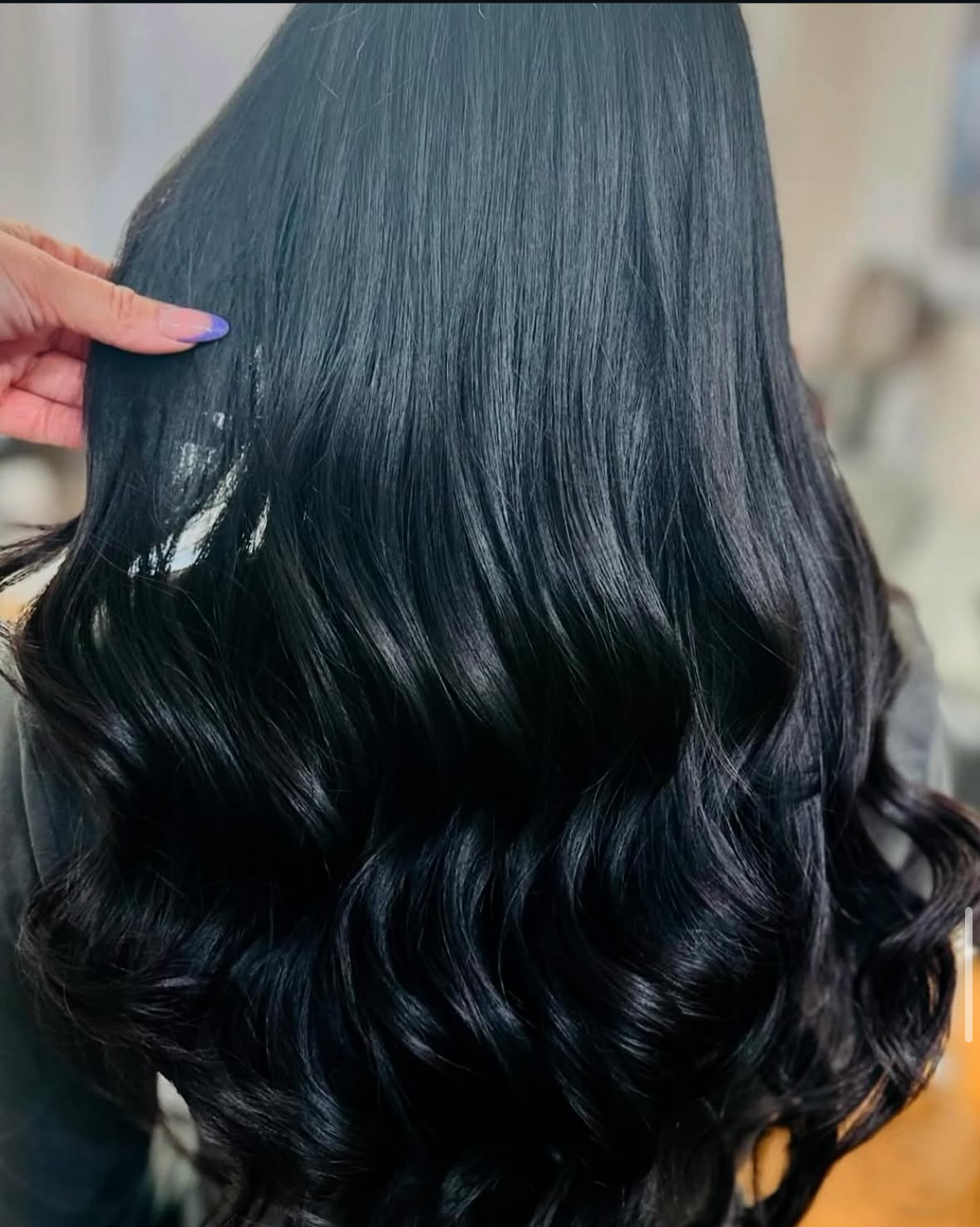 Long, shiny, black wavy hair. Hand touching hair near top