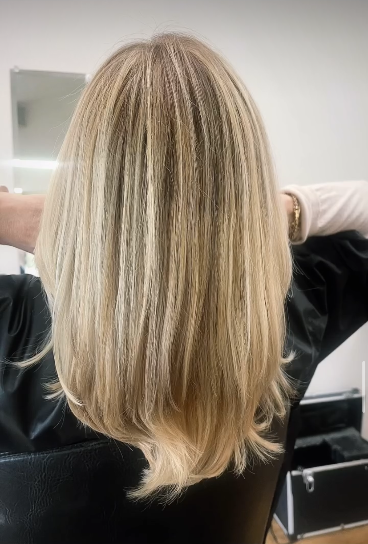 Blonde crimped hair in a salon chair, angled from the back