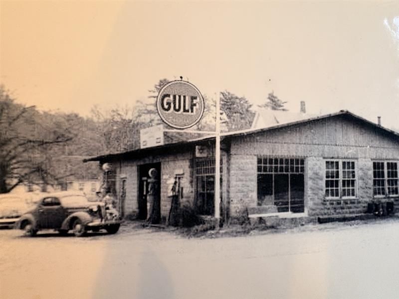 Old Gulf gas station with a vintage car parked outside in a sepia-toned scene