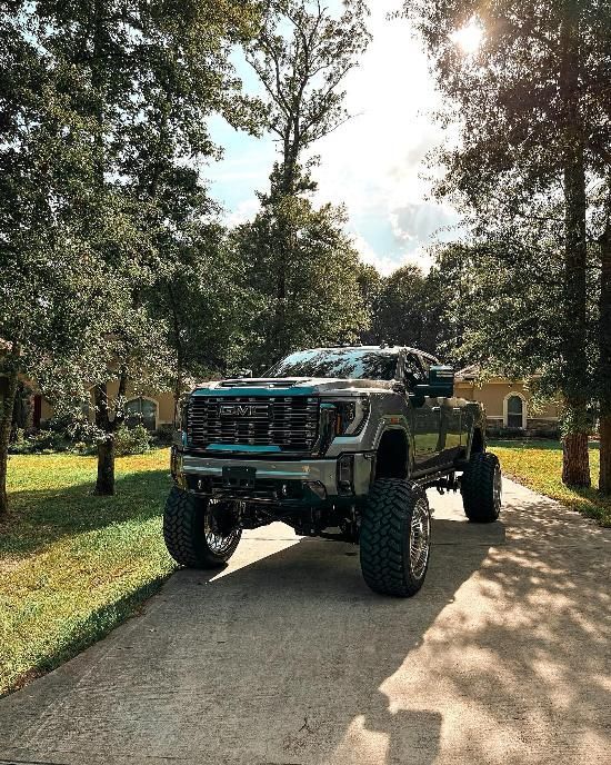 A gmc sierra pickup truck is parked on a driveway in front of a house.