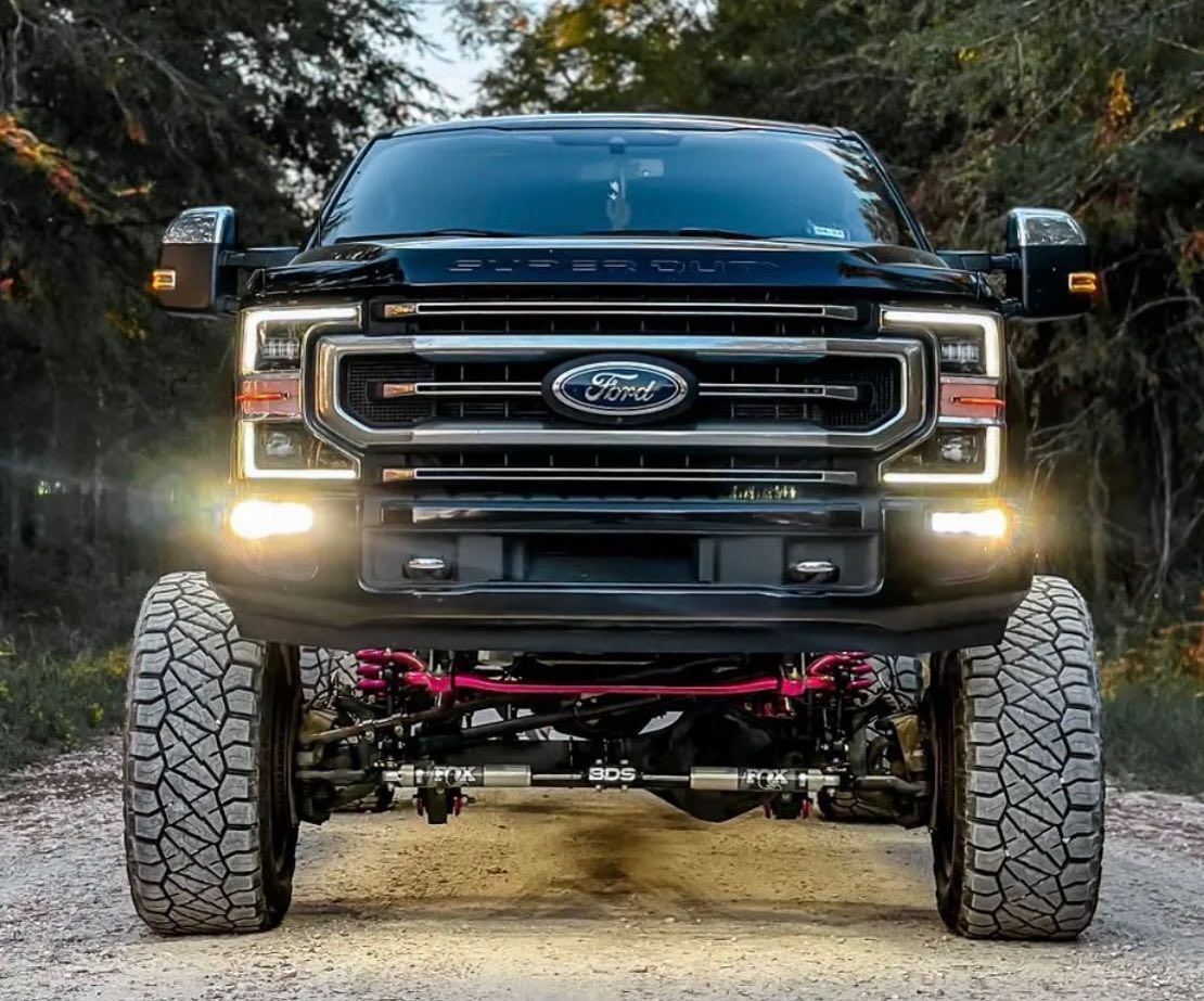 A black ford truck is parked on a dirt road.