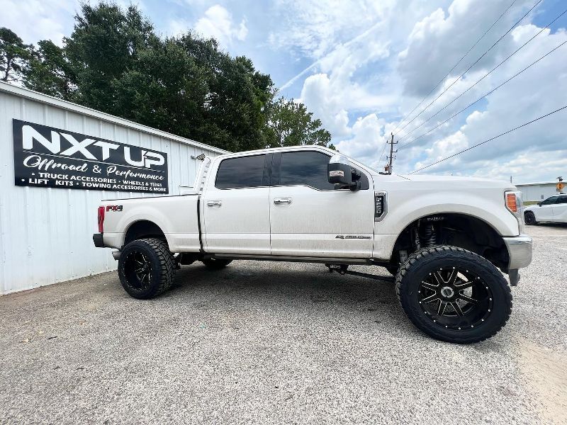 A white truck is parked in front of a building with a sign that says nxt up.