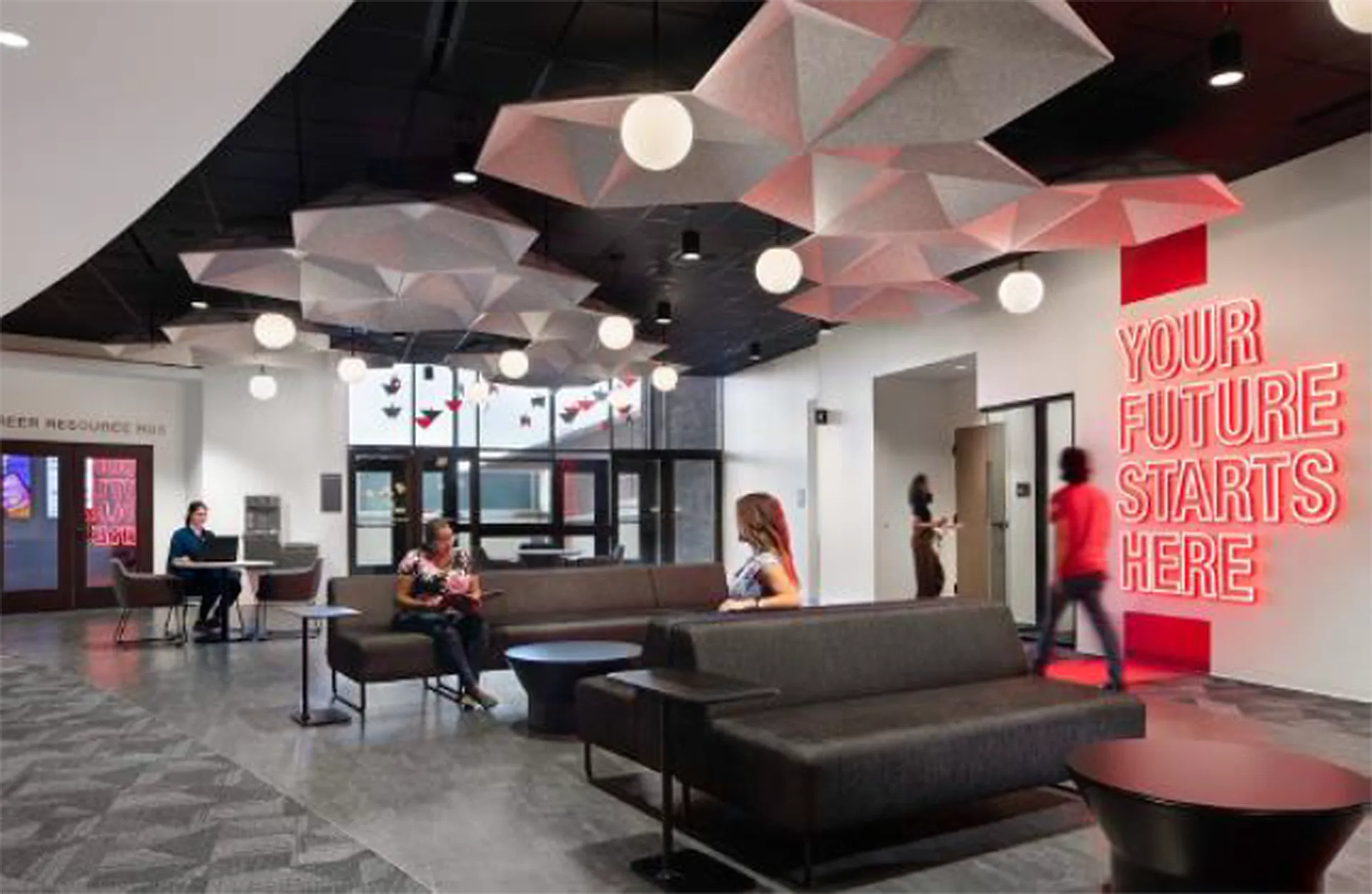 Lounge area with geometric ceiling features, sofas, and neon sign: