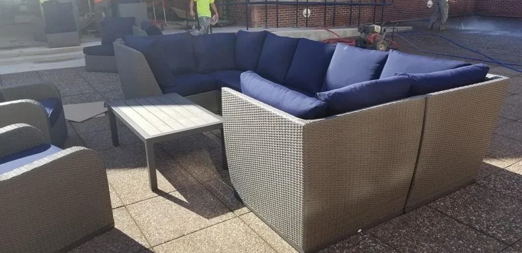 Outdoor sectional sofa with blue cushions and a small table on a patio.