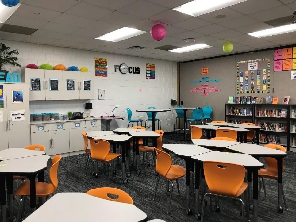 Classroom with orange chairs, white desks, bookshelves, and decorative balloons.