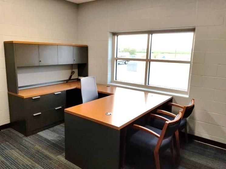 Office with a dark L-shaped desk, built-in cabinet, window, and two chairs.