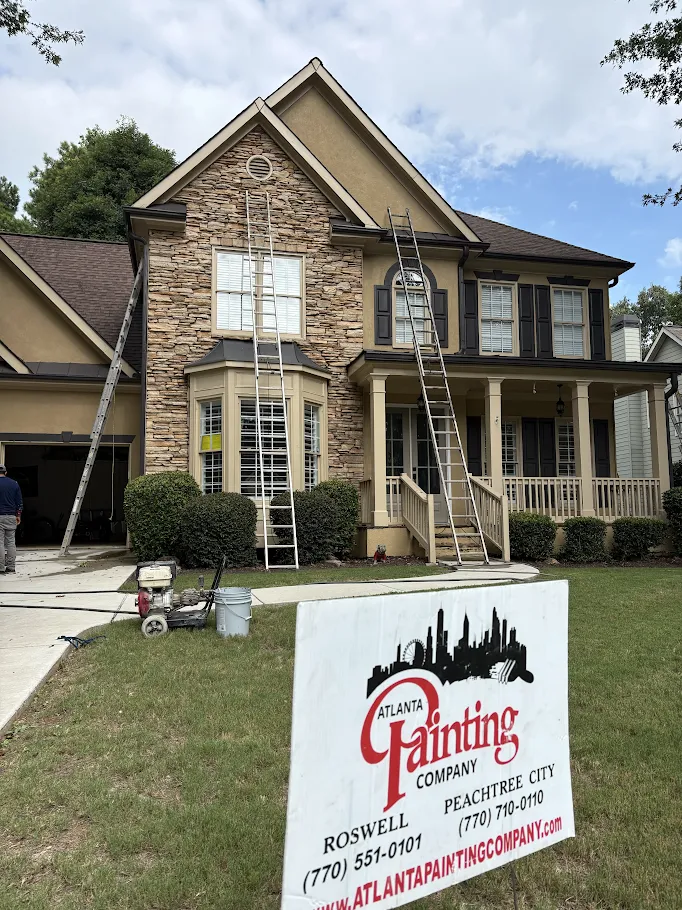 Suburban house with a Atlanta Painting Company sign in the front yard and painting supplies on the lawn