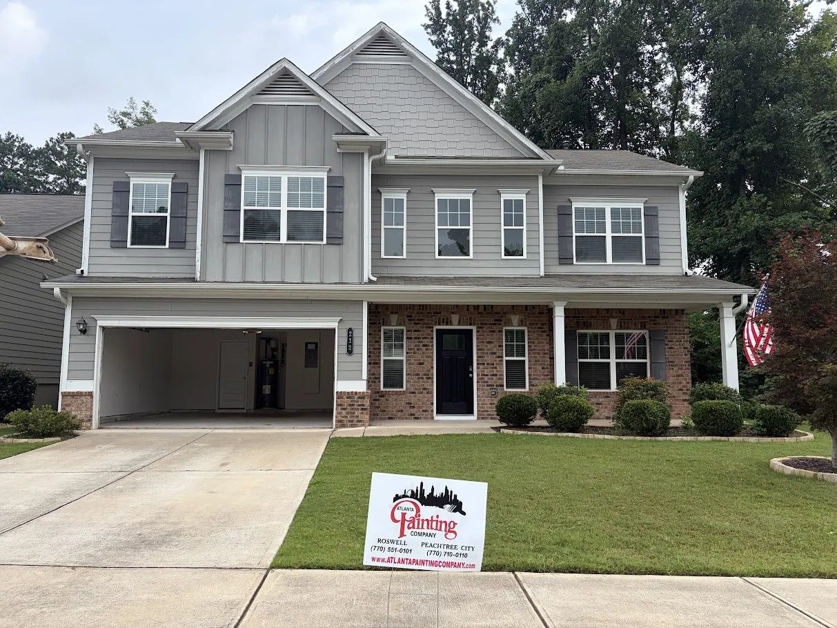 Two-story gray house with a Atlanta Painting Sign front lawn and a real estate sign in the yard