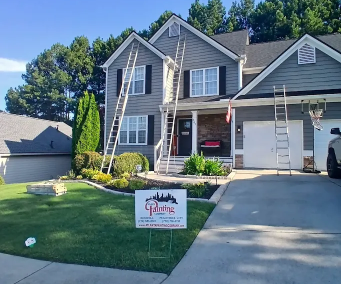 Suburban house with driveway, lawn, and a Atlanta Painting Sign yard sign in front of the garage.