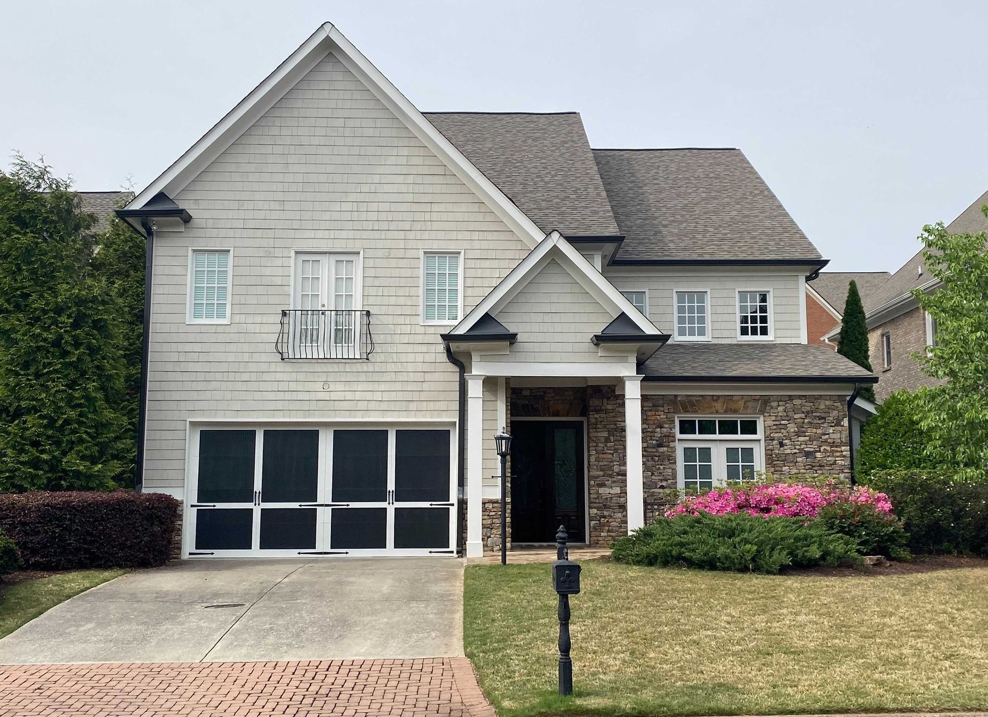 Two-story house with gray siding, stone accents, and a garage. Landscaping in front.