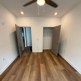Empty room with hardwood floors, two doorways, and a ceiling fan.