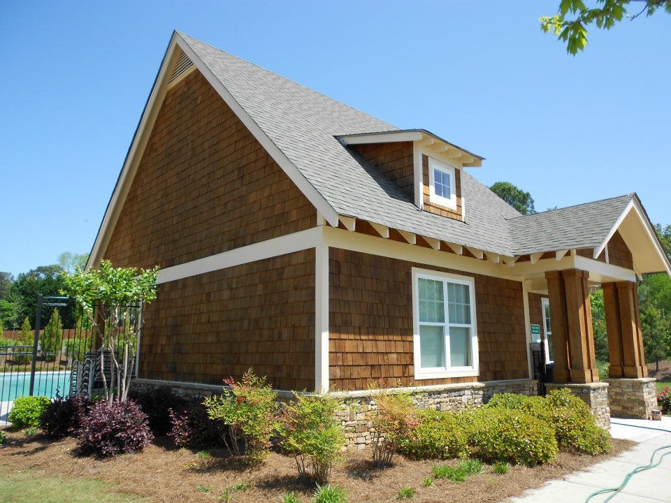 A brown house with a gray roof and white windows