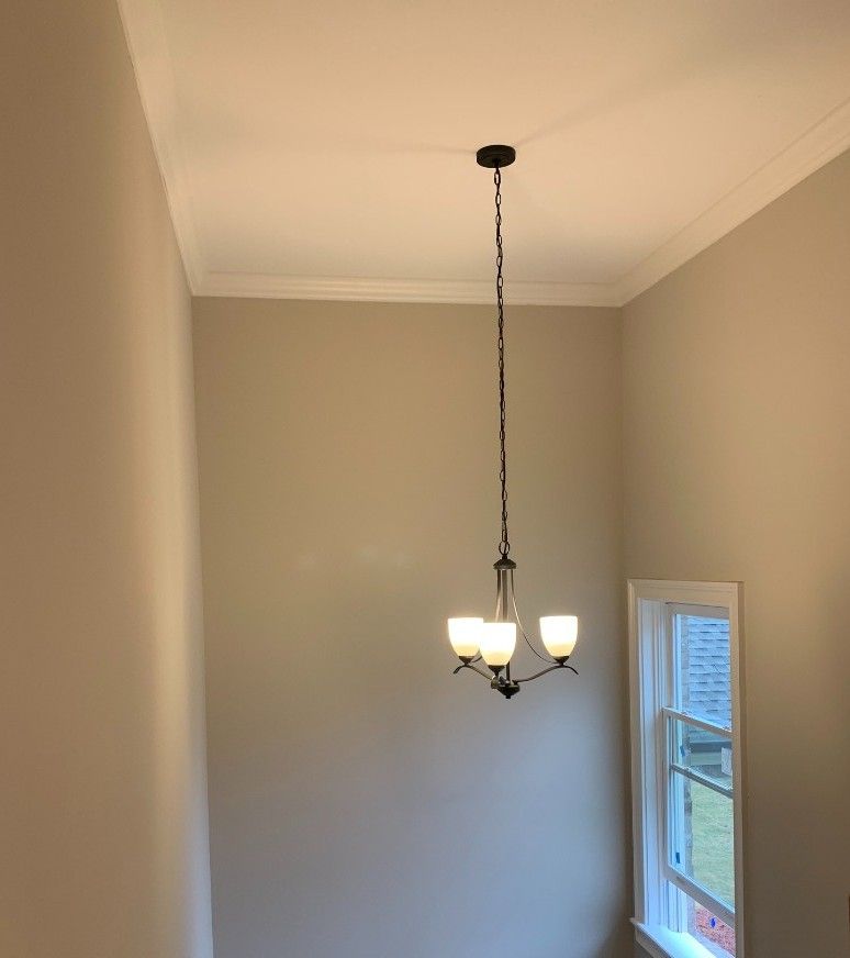 A chandelier is hanging from the ceiling in a room next to a window.
