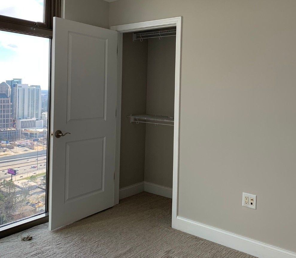 An empty bedroom with a walk in closet and a large window.