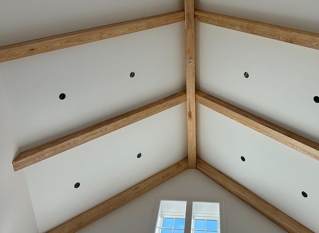 The ceiling of a room with wooden beams and a window.