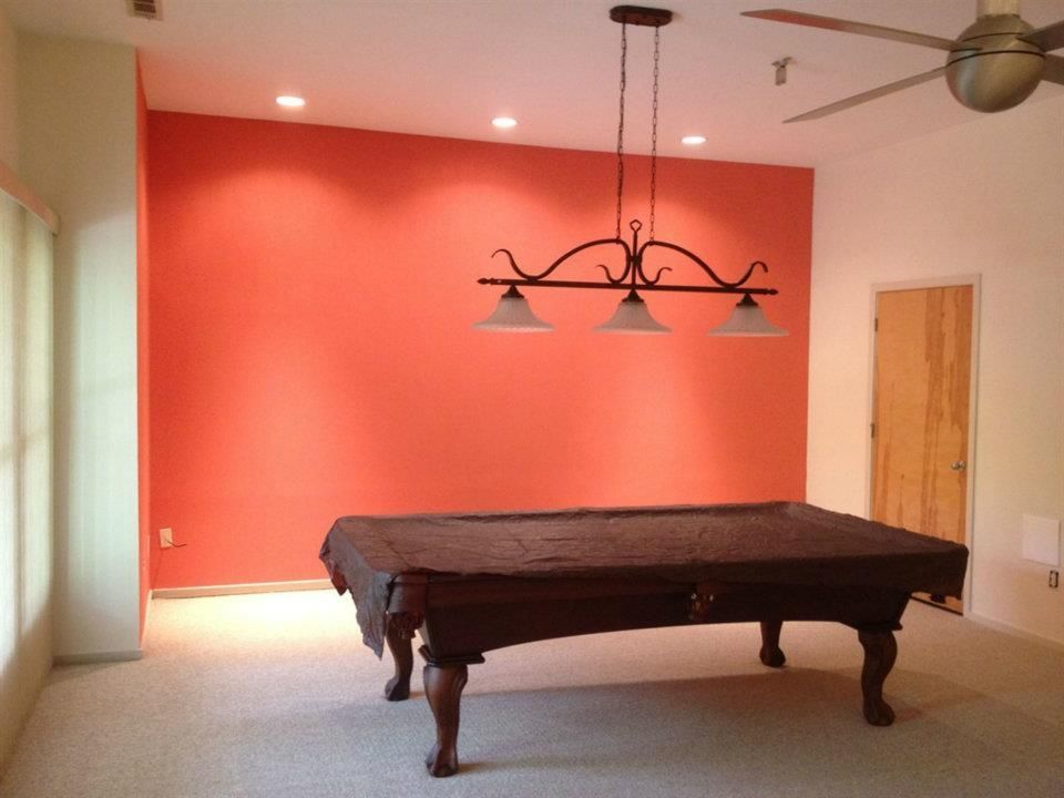 A pool table in a room with red walls and a ceiling fan