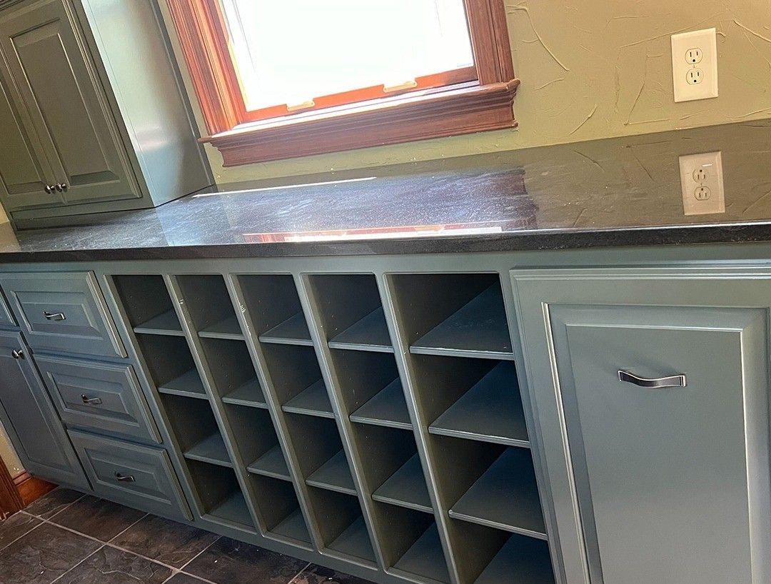 A kitchen with a lot of cabinets and shelves and a window.