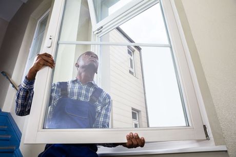 A man is installing a window in a house.