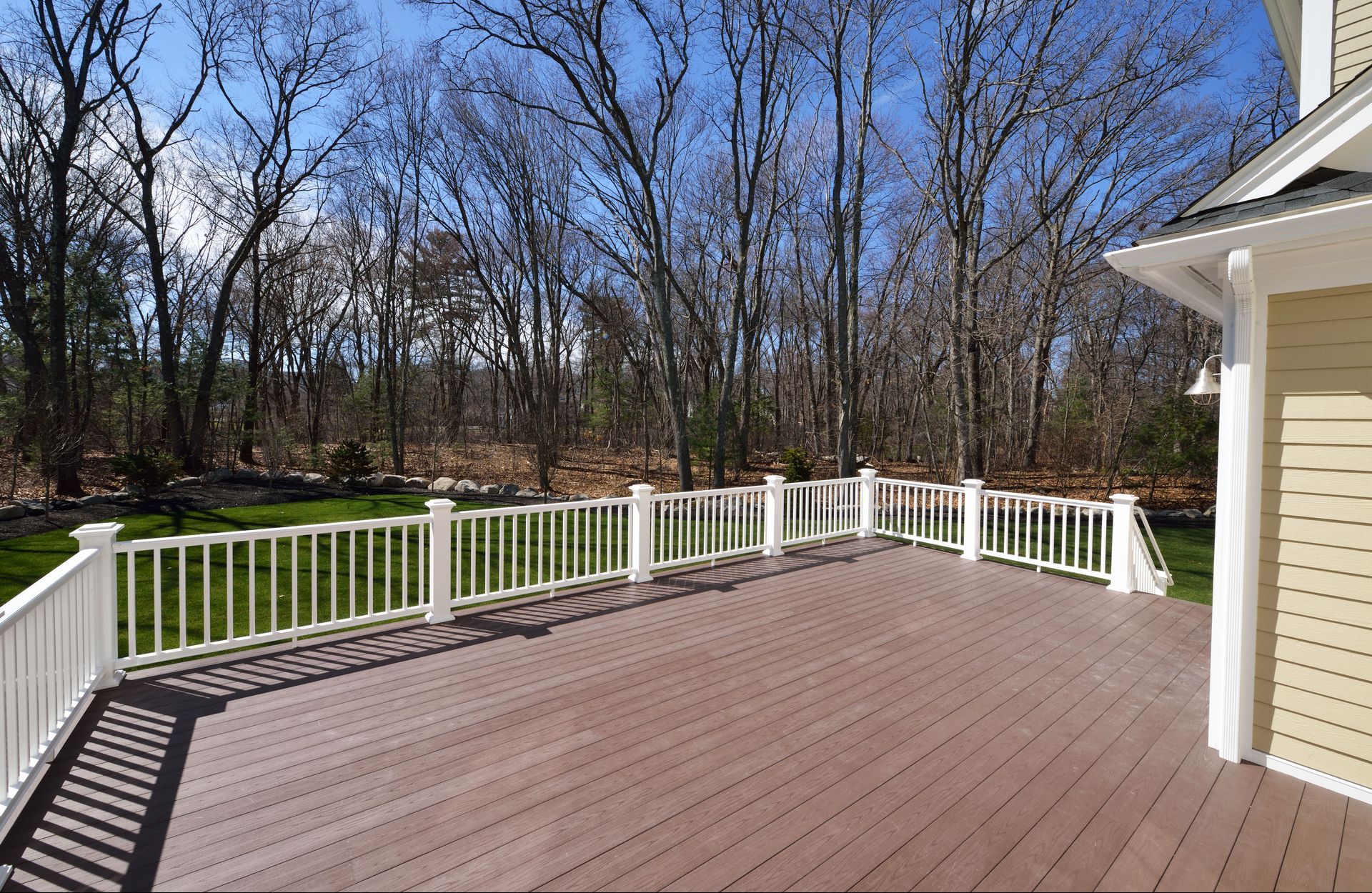 A large deck with a white railing and trees in the background