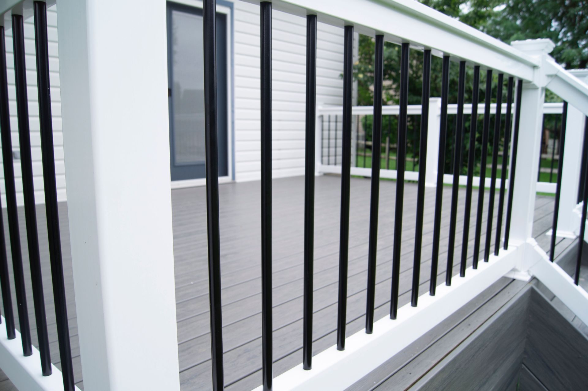 A deck with a white railing and black bars.