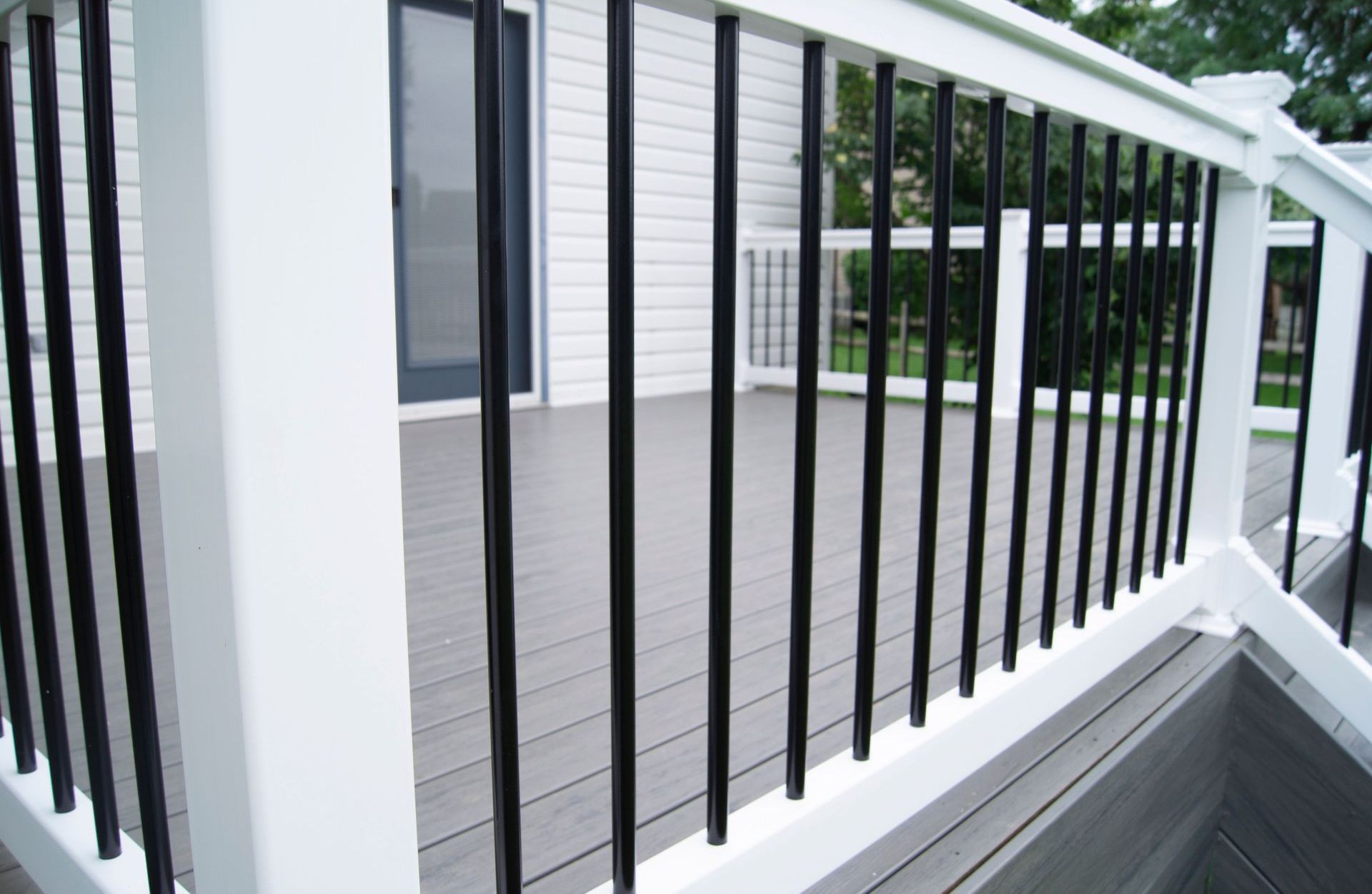 A deck with a white railing and black bars.