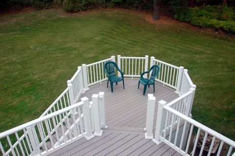 A wooden deck with stairs and a table and chairs in front of a house.